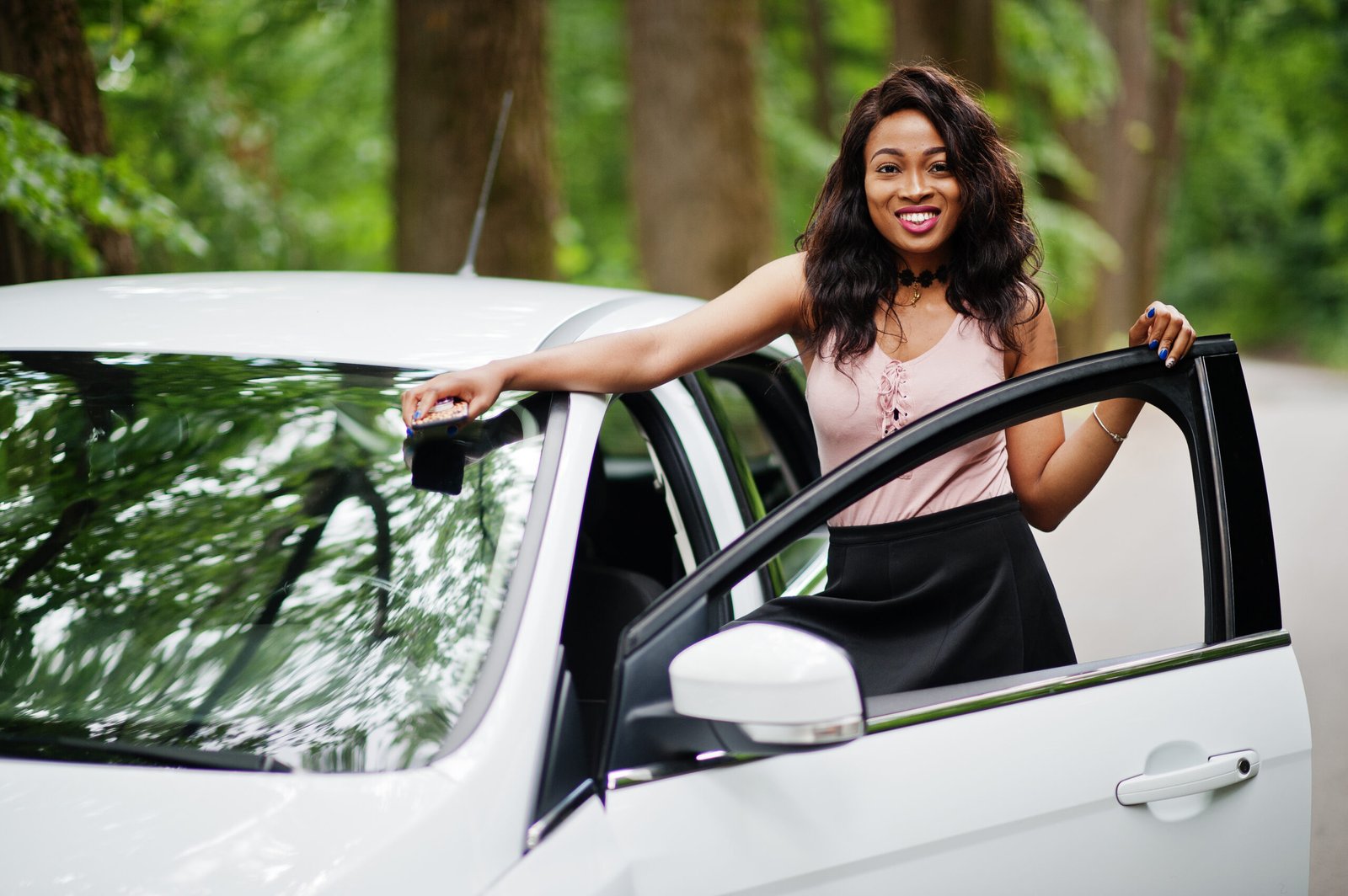 African american woman posed against white car in forest road.